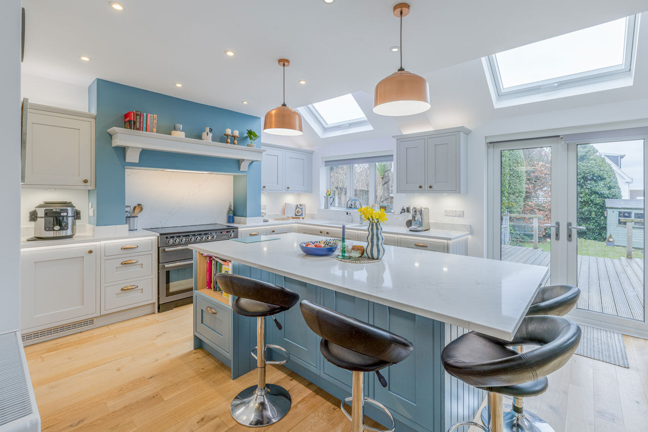 Modern kitchen with white countertops, blue cabinets, and skylights.